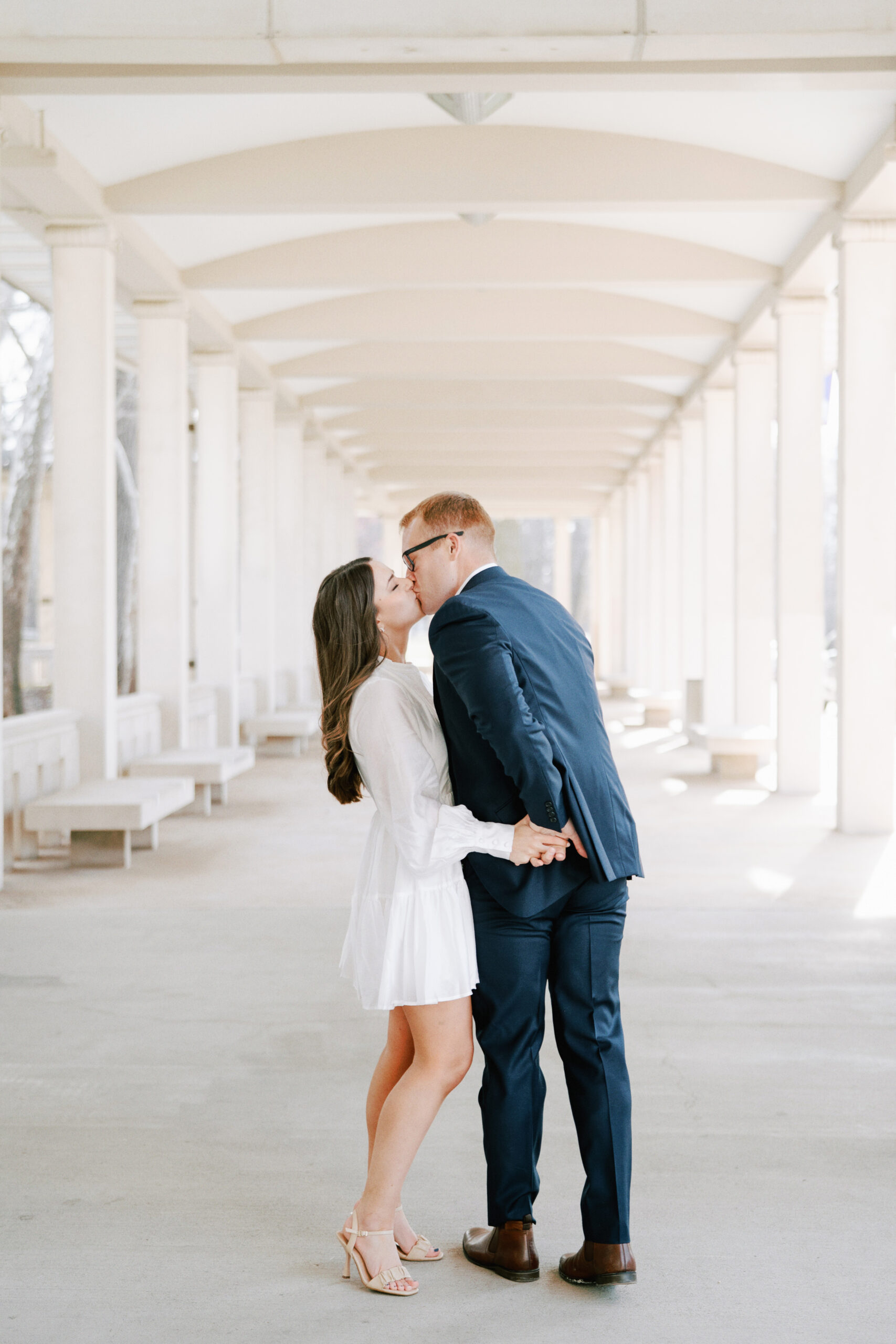Man and woman kiss during their engagement session at the Muny in St. Louis
